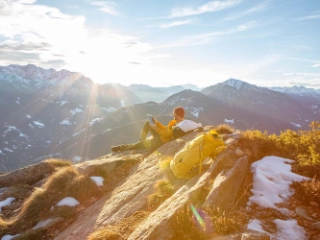 Mann auf einem Felsen, der waehrend seiner Wanderung eine Pause macht und sich entspannt, dient als Symbolbild für die Themen Anlegen und Kassenobligation.